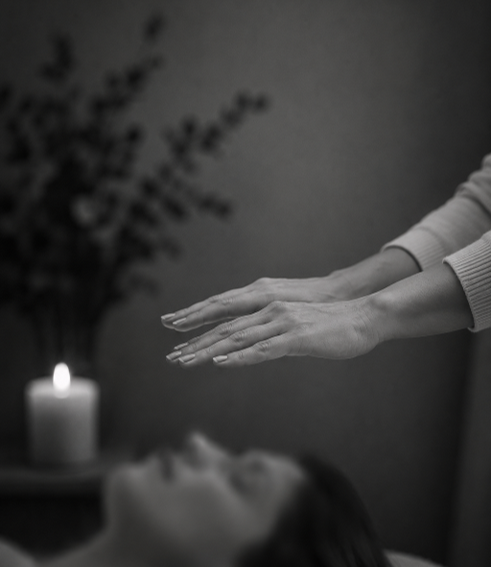 Hands placed gently above a client during a Reiki healing treatment